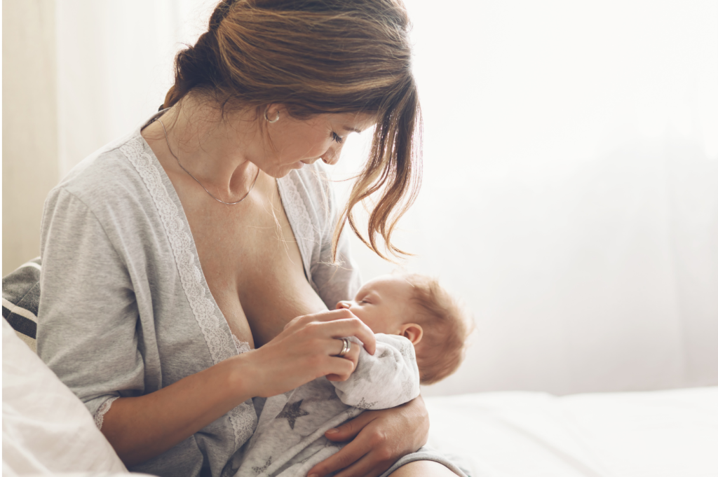 Photo d'une maman assise sur un lit qui allaite son bébé
